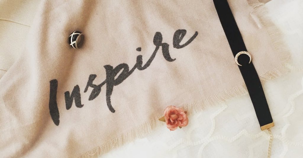 Stylish composition featuring fashion jewelry and decor items with inspiring text on fabric.