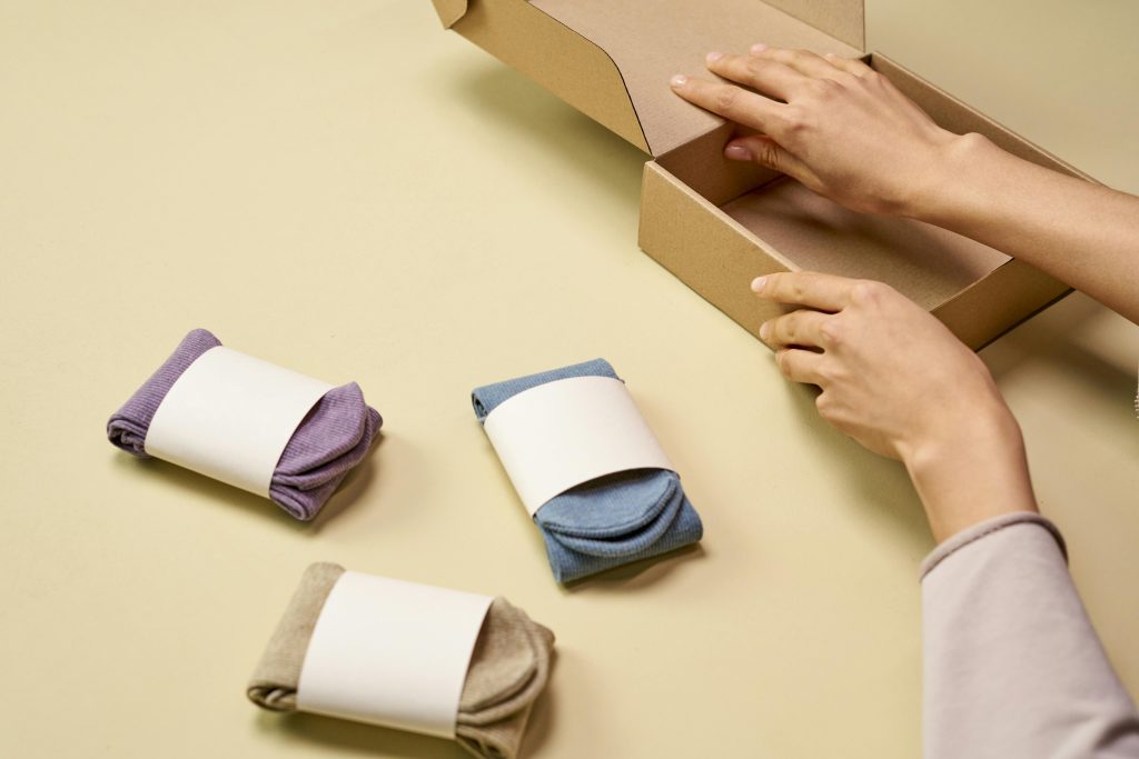 Hands packaging colorful socks into a cardboard box for shipment or storage.